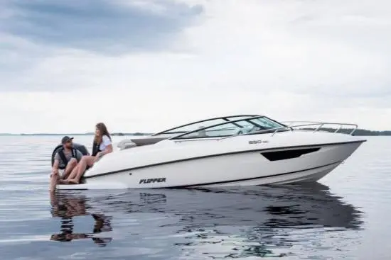 A couple relaxes on a white Flipper boat on calm waters under a cloudy sky, showcasing leisure and boating enjoyment.